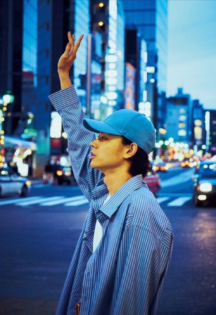 a man standing on the side of a road holding his hand up in the air