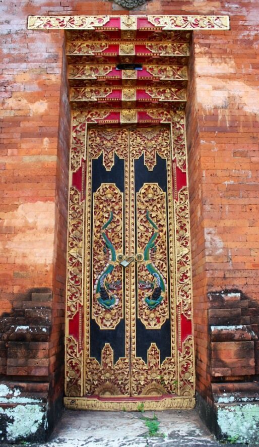 an ornately decorated door in front of a brick wall