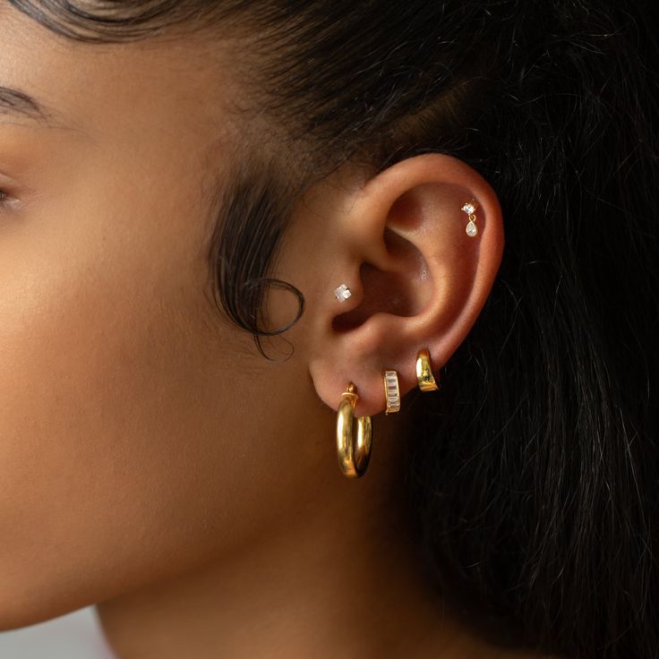 a close up of a person with ear piercings on their ears and wearing gold jewelry