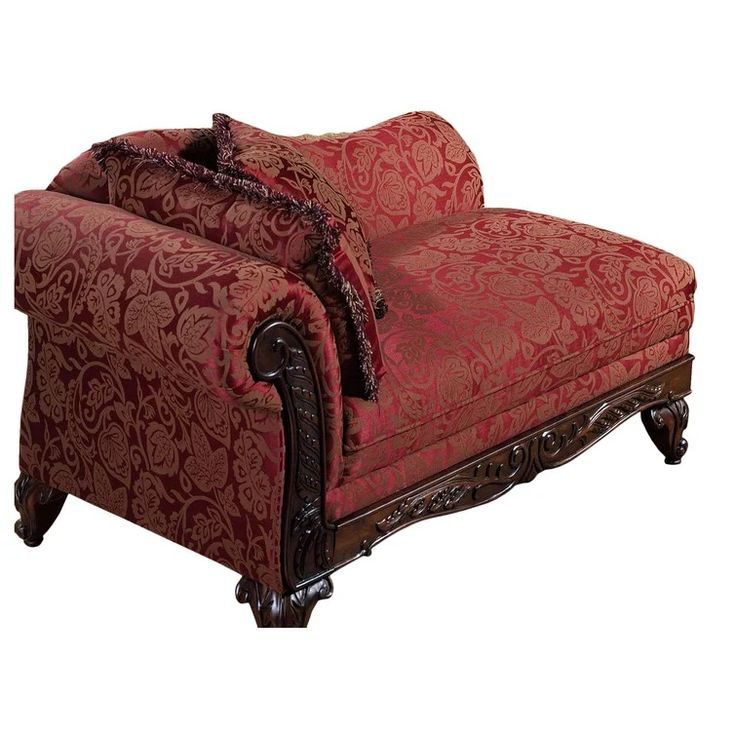 a red couch with ornate carvings on the armrests and foot rest, sitting in front of a white background