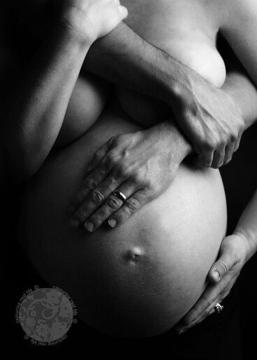 a black and white photo of a pregnant woman's belly with her hands on her stomach