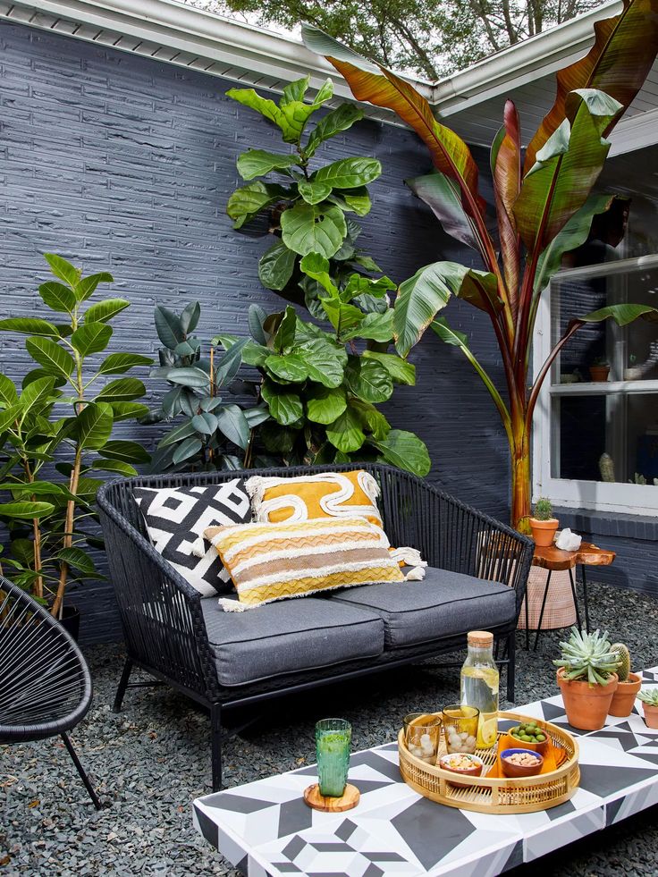 an outdoor living area with black and white furniture, potted plants and decorative pillows