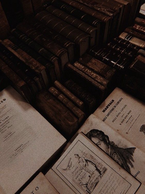 an open book sitting on top of a table next to stacks of books and papers