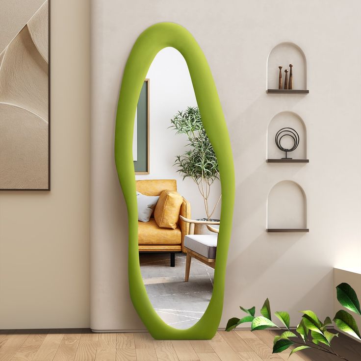 a green oval shaped mirror sitting on top of a wooden floor next to a wall