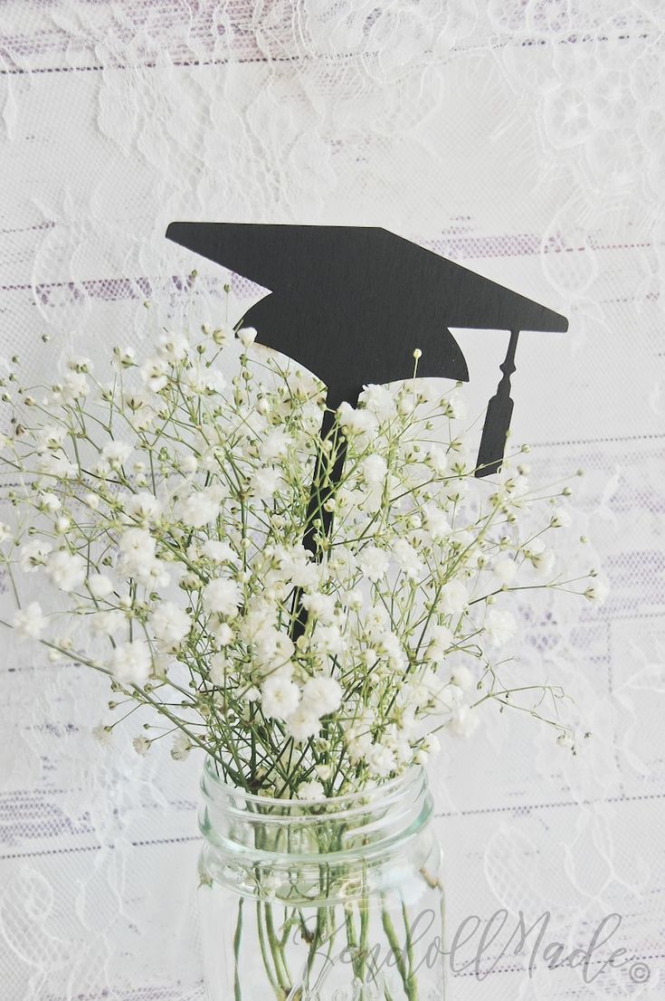 a mason jar filled with flowers and a graduation cap cutout on top of it