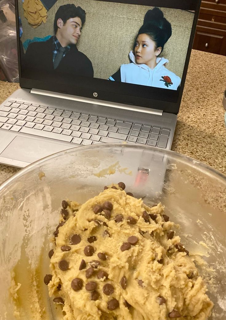 an open laptop computer sitting on top of a counter next to a bowl of food