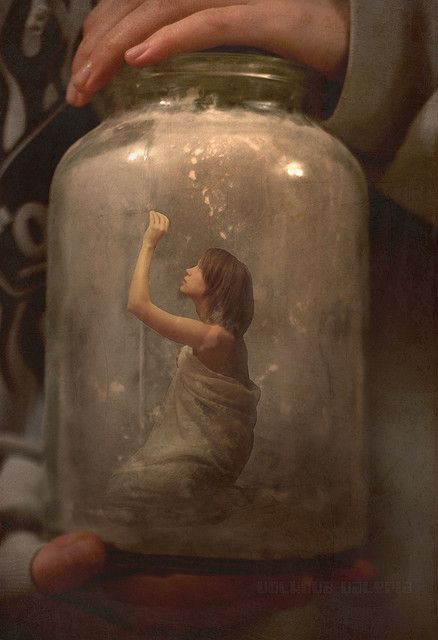 a person holding a glass jar with a painting on it