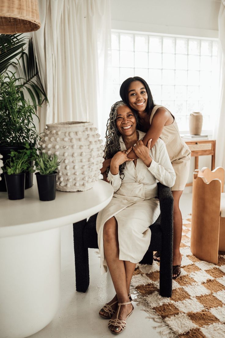 two women hugging each other in front of a table with potted plants on it