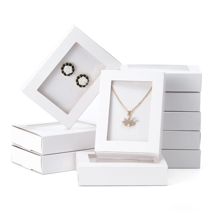 three white boxes with two necklaces and one earring in them on a white background