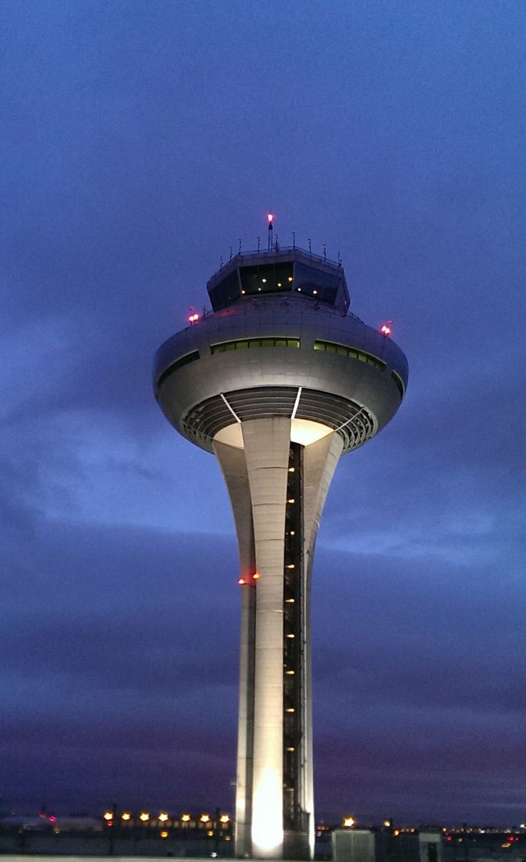 an airport control tower lit up at night with lights on it's sides and the sky in the background