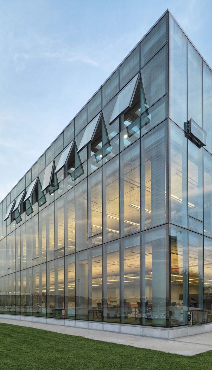 a large glass building sitting on top of a lush green field