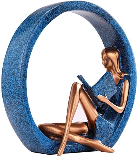 a figurine sitting on top of a blue moon with a book in it's lap