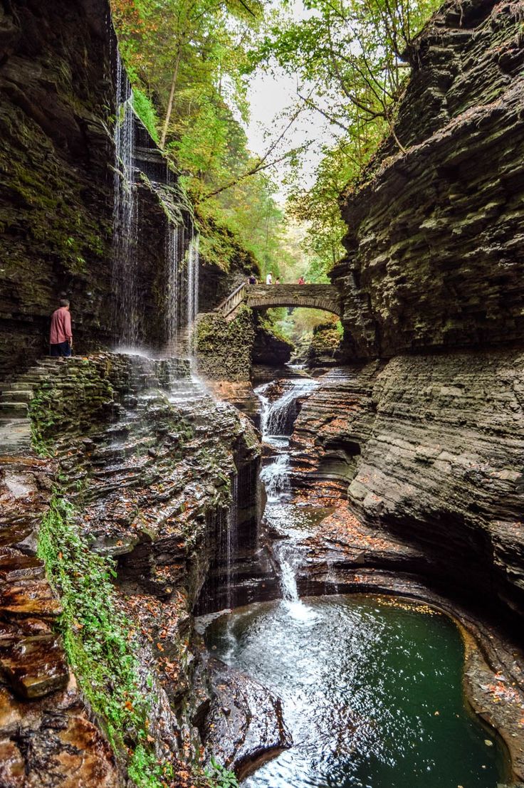 a person standing at the base of a waterfall