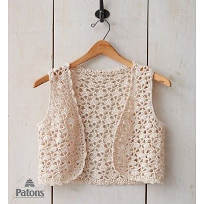 a crocheted crop top hanging on a wooden wall next to a coat rack