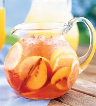 a pitcher filled with fruit sitting on top of a wooden table