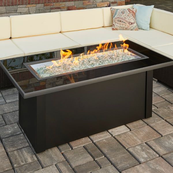 a fire pit sitting on top of a brick patio next to a white couch and table