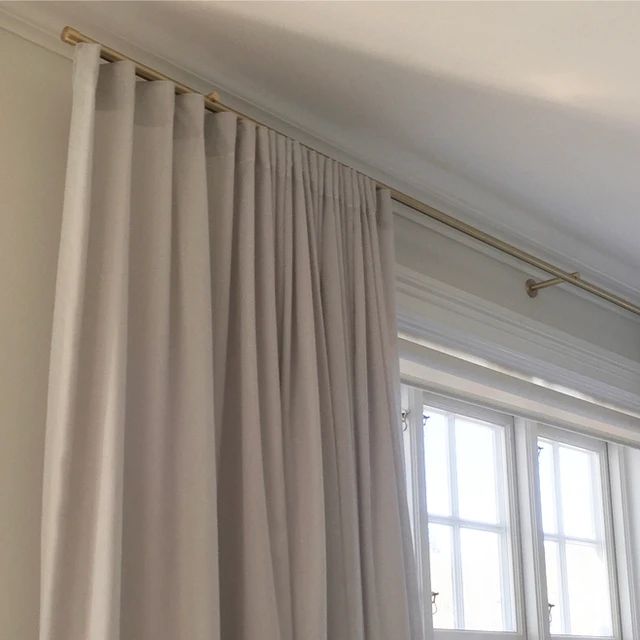 the curtains are hanging in front of the window with white drapes and gold hardware