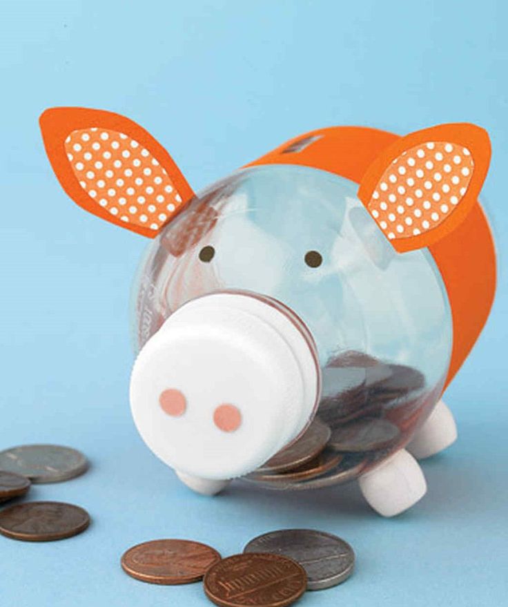 a piggy bank sitting next to some coins on a blue surface with an orange nose