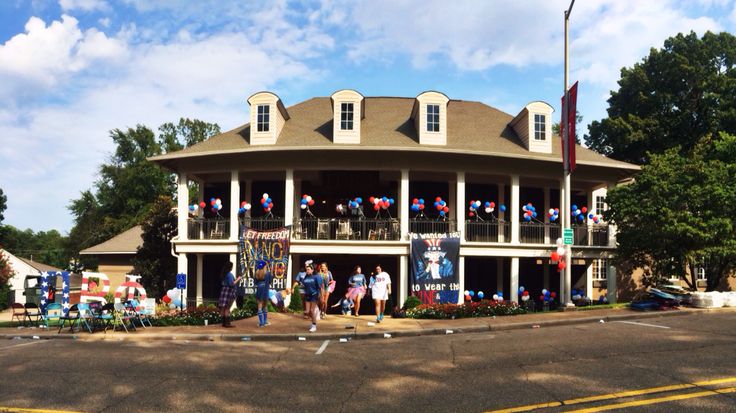 a large building with people standing in front of it on the side of the road