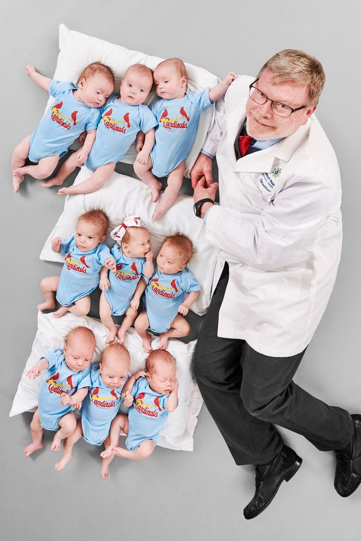 a man in a lab coat standing next to a bunch of babies