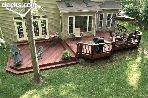 a backyard deck with chairs and an umbrella