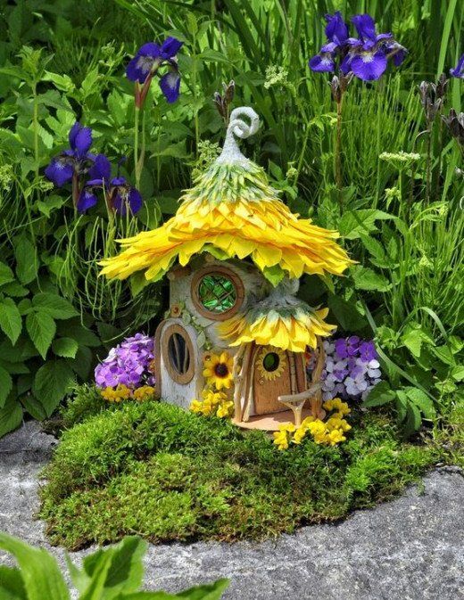 a bird house with flowers and plants around it