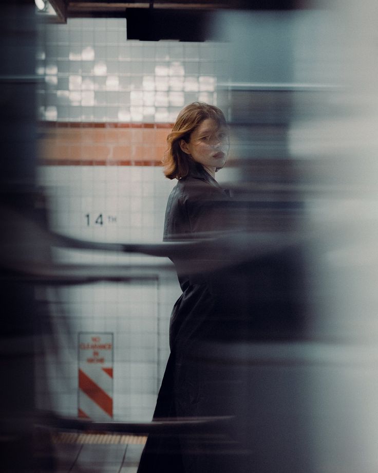 a woman standing in front of a tiled wall