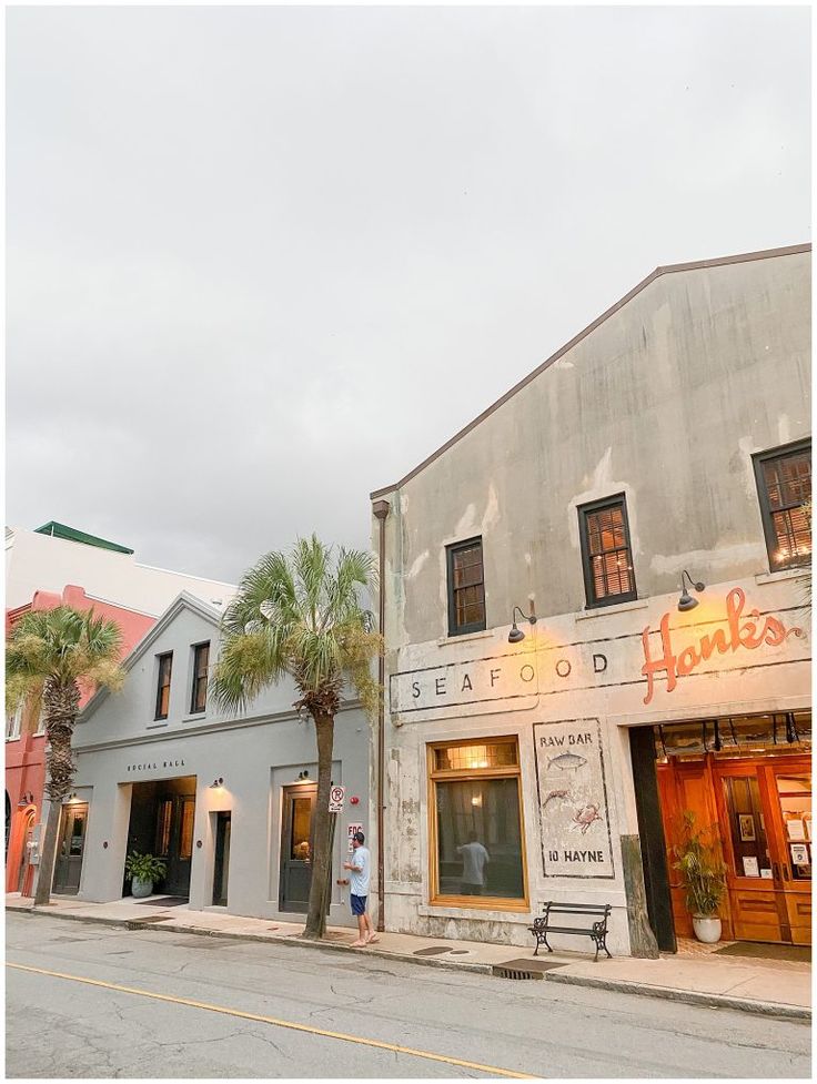 an old building with palm trees in front of it and people walking on the sidewalk