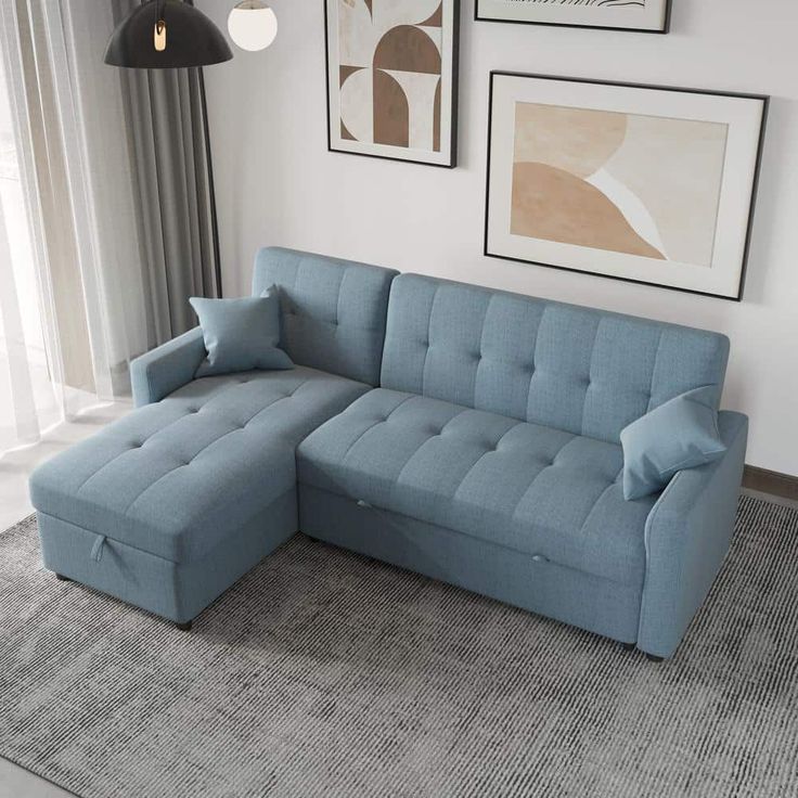 a blue sectional sofa sitting on top of a rug in front of a wall with pictures above it