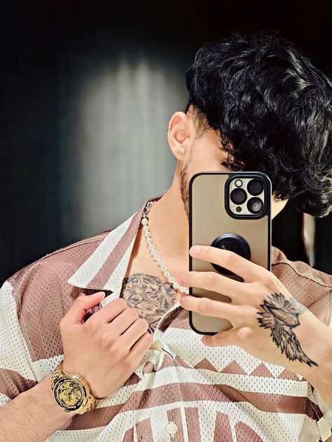 a man taking a selfie with his phone in front of him and tattoos on his arm