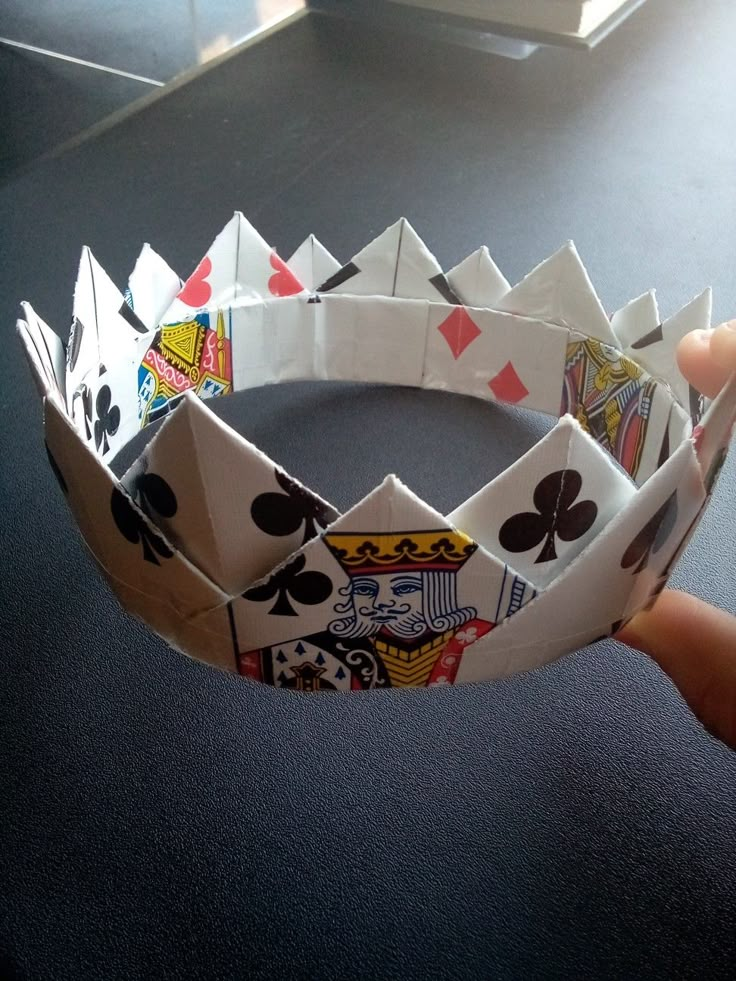 a person holding up a paper crown made out of playing cards