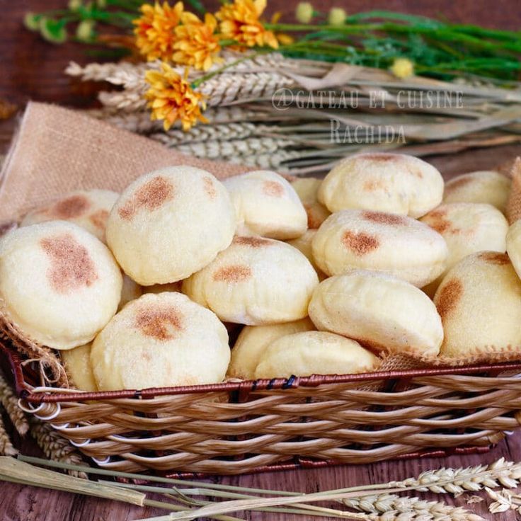 a basket full of cinnamon buns sitting on top of a table next to flowers