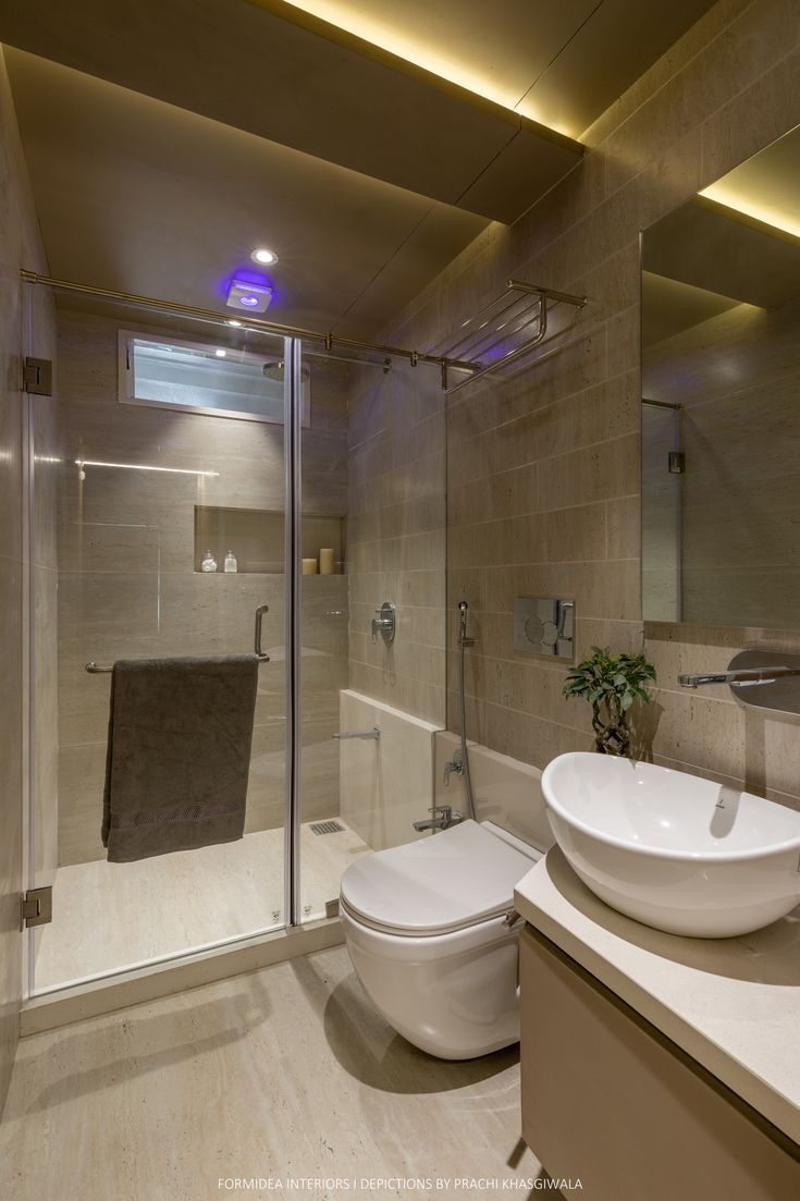 a bathroom with a sink, toilet and shower stall in the middle is illuminated by recessed lighting