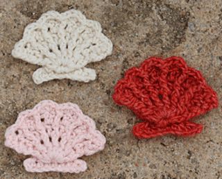 three crocheted scallops sitting on top of a stone slab next to each other