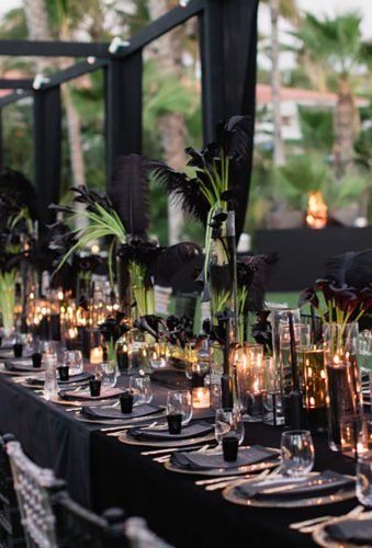 a long table is set with candles and black linens for an elegant dinner party