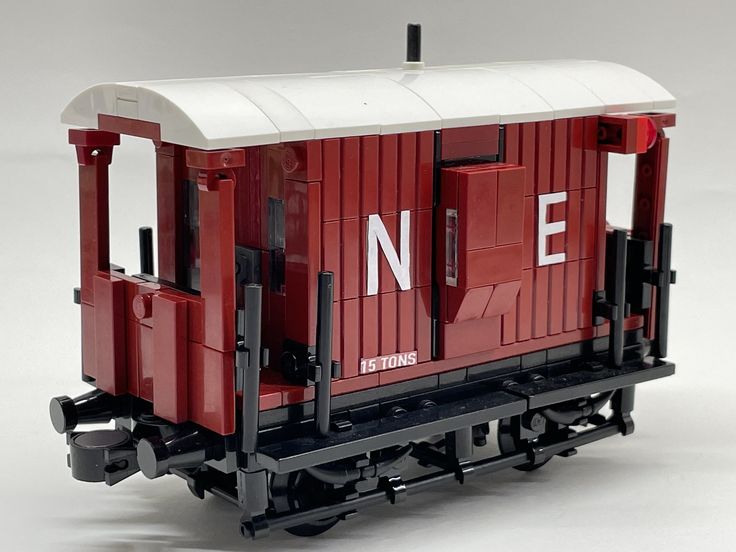 a red and white train car sitting on top of a table next to a wall