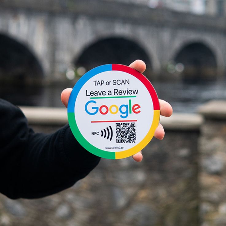 a person holding up a google sticker in front of a bridge