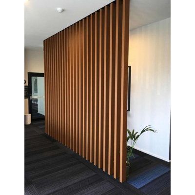 an office with wood slats on the wall and black flooring in front of it