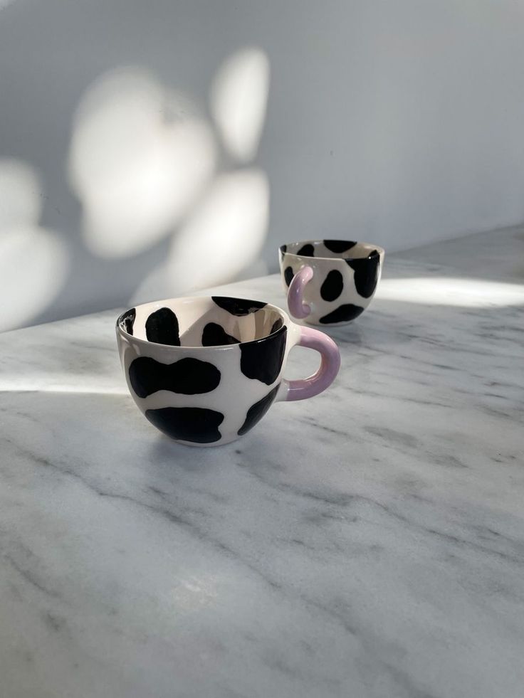 two black and white cups sitting on top of a marble counter next to each other