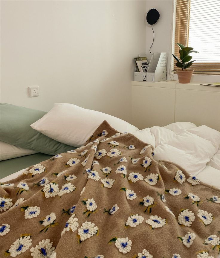 an unmade bed with white and blue flowers on it