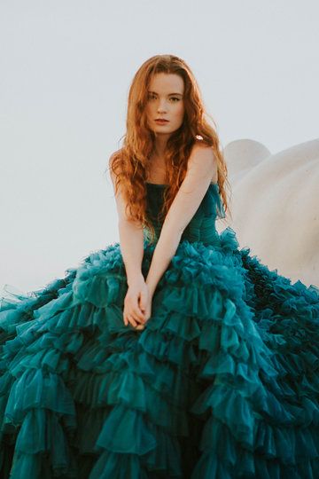 a woman in a green dress sitting on top of a rock