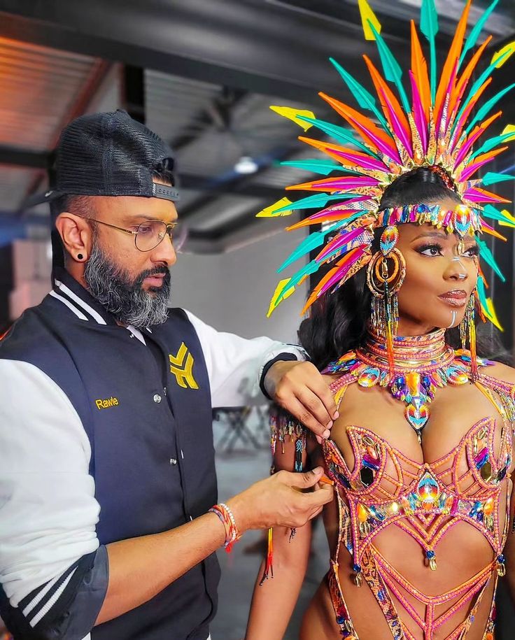 a man standing next to a woman in a bodysuit with colorful decorations on her head