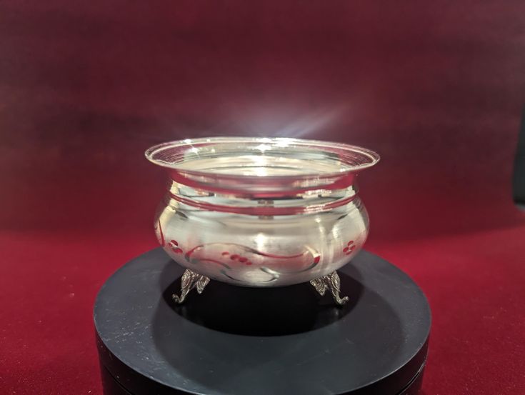 a glass bowl sitting on top of a black stand next to a red tablecloth