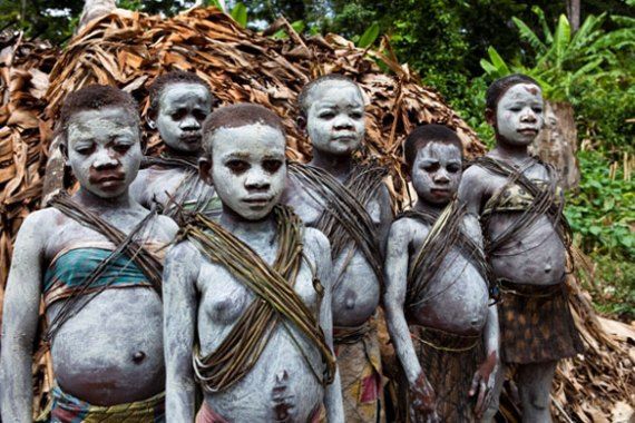 a group of people standing next to each other in front of a pile of sticks