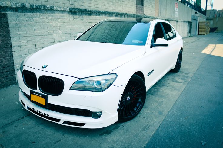 a white car parked in front of a brick wall