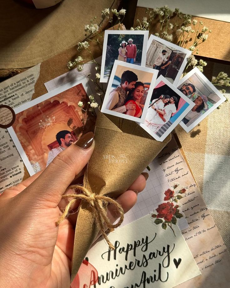 a hand holding a paper cone with pictures on it and some cards attached to it