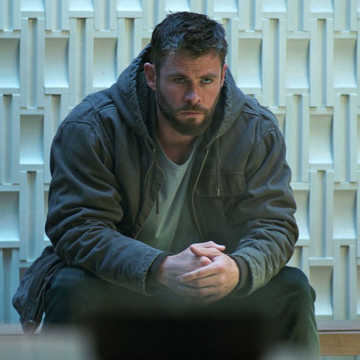 a man sitting on the ground in front of a wall with white blocks behind him