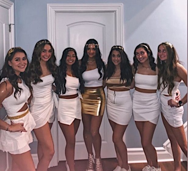 a group of women standing next to each other in front of a door wearing white dresses