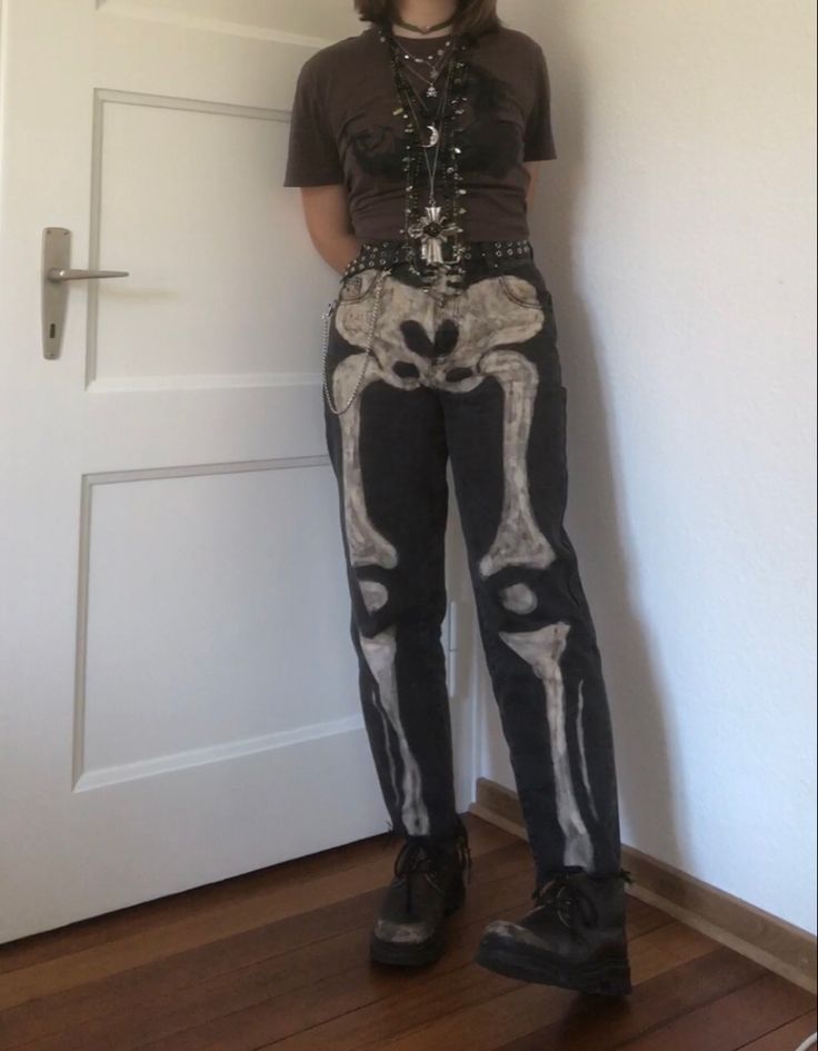 A mid-sized person/girl wearing a brown cropped shirt with a black ape on it and black jeans with bleached skeleton bones on them and a black leather belt, dark brown oxford shoes and multiple crystal rings and bracelets. 		The person is also wearing multiple silver necklaces. Bleach Shirt Art Aesthetic, Skeleton Jeans Diy, Skeleton Bleached Jeans, Pants Ideas Diy, Skeleton Aesthetic Outfit, Tech Core Outfits, Bleaching Ideas Clothes, Skeleton Inspired Outfit, Jeans Bleach Ideas