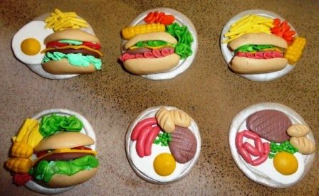 four plates with hamburgers, fries and corn on them sitting on a counter top